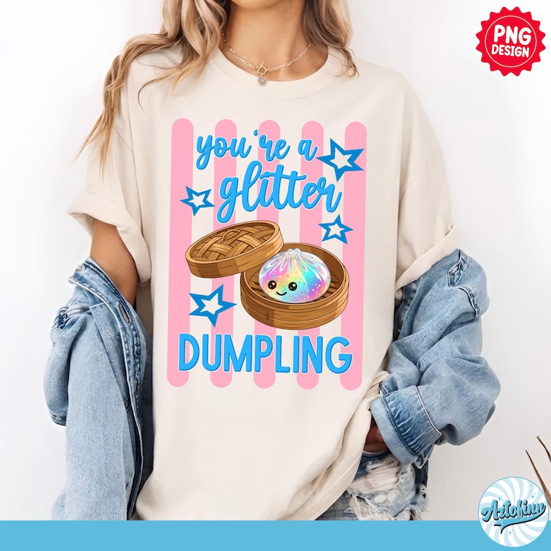 May include: Cream-colored t-shirt with a graphic of a dumpling in a bamboo steamer. The text reads "you're a glitter DUMPLING" in blue, with pink stripes and blue stars. The design is a PNG design.