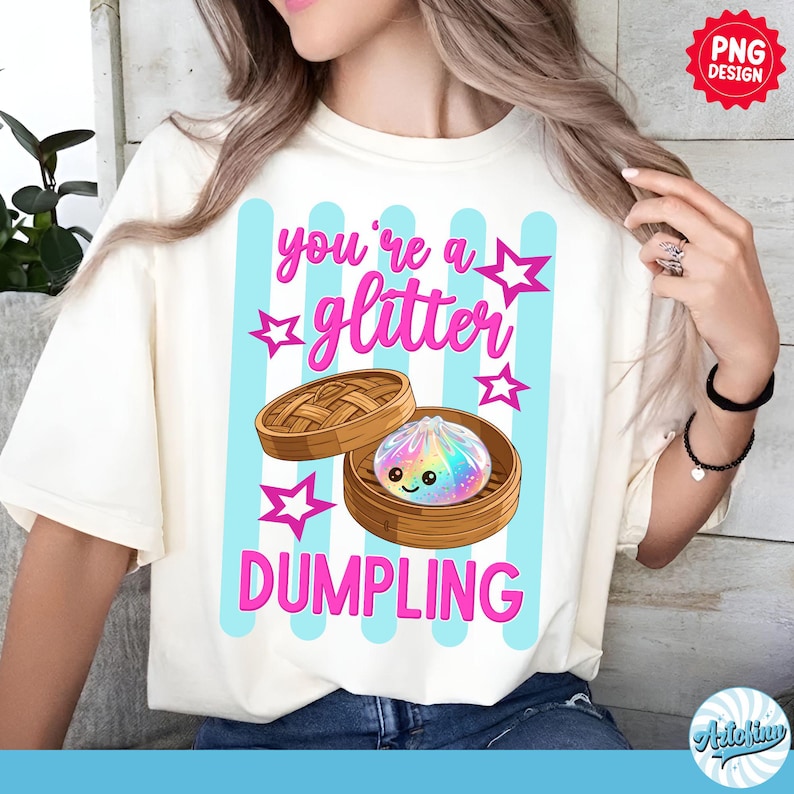May include: Cream-colored t-shirt with a graphic of a dumpling in a bamboo steamer. The text "you're a glitter DUMPLING" is in pink, with blue vertical stripes and star accents. The design is a PNG.