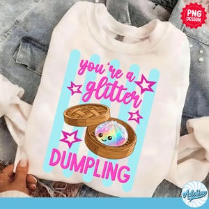 May include: White sweatshirt with a graphic that says "you're a glitter dumpling." The design features a cartoon dumpling with a rainbow-colored filling inside a bamboo steamer, with pink stars and blue stripes.