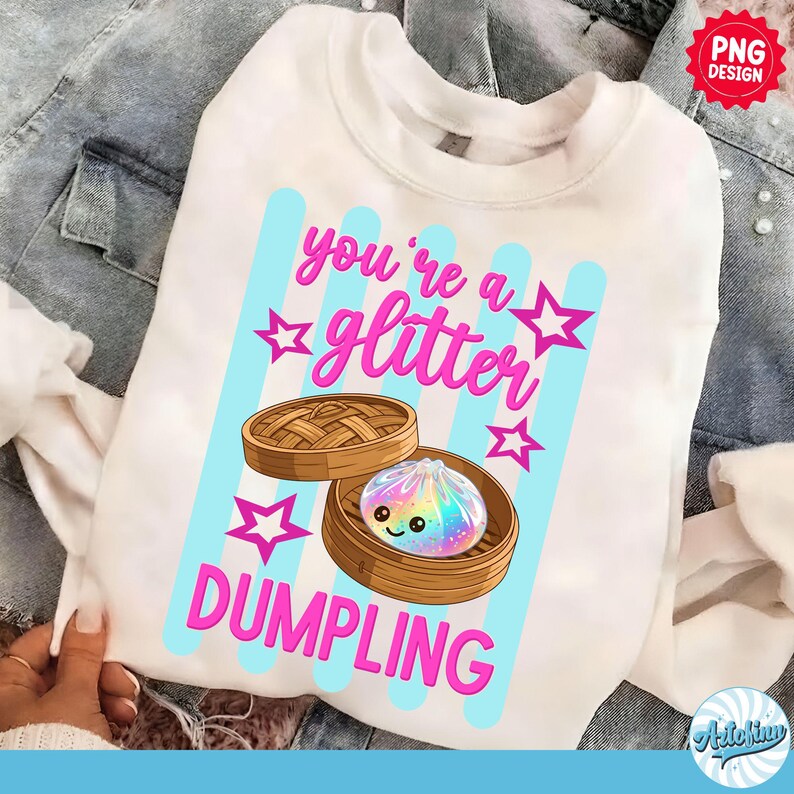May include: White sweatshirt with a graphic that says "you're a glitter dumpling." The design features a cartoon dumpling with a rainbow-colored filling inside a bamboo steamer, with pink stars and blue stripes.