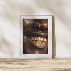 Puede incluir: Una impresión artística enmarcada que presenta un primer plano de una cara sonriente con dientes de oro. La obra de arte es una pintura con tonos cálidos, que muestra los labios, la nariz y una parte de la cara. La impresión está en un marco blanco, sobre una pared neutra.