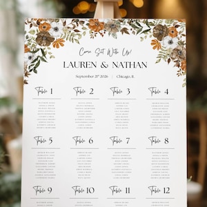 May include: A wedding seating chart with the text "Come Sit With Us! LAUREN & NATHAN September 21st 2026 Chicago, Il." Floral accents in brown, white, and orange frame the top. Twelve tables are listed with guest names.