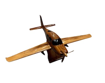 Puede incluir: Un modelo de avión de madera con un esquema de pintura marrón y negro. El avión tiene una hélice y está en vuelo.