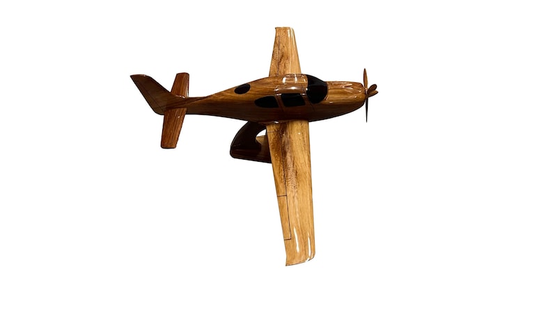 May include: A wooden model airplane with a brown and black paint scheme. The model is detailed with a propeller and windows.