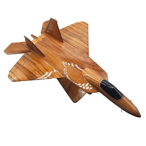 May include: A wooden model of a fighter jet, featuring a detailed design with a brown finish and a black cockpit. The wings and body are intricately carved, showcasing the natural wood grain. This decorative piece is a great gift for aviation enthusiasts.