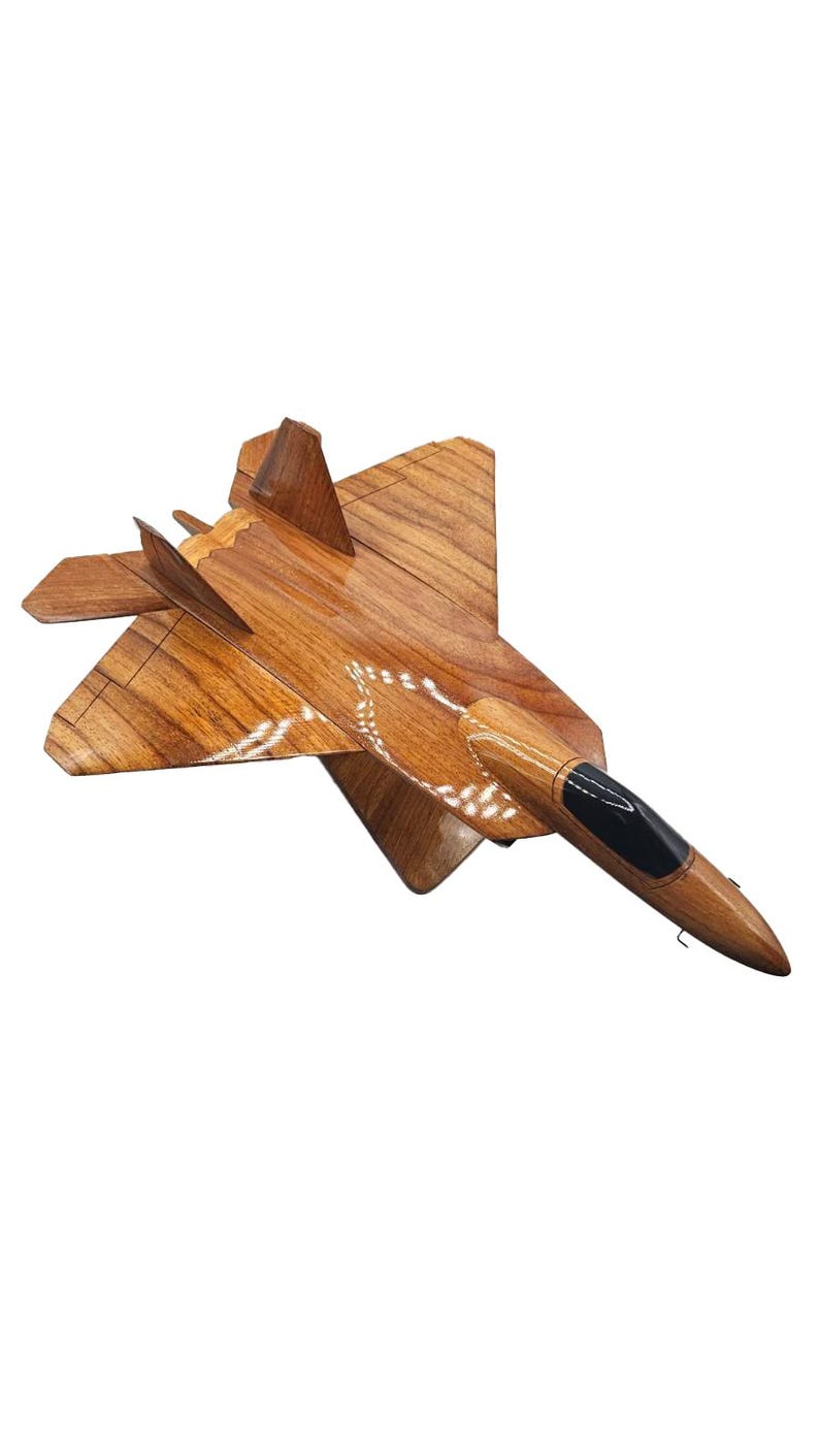 May include: A wooden model of a fighter jet, featuring a detailed design with a brown finish and a black cockpit. The wings and body are intricately carved, showcasing the natural wood grain. This decorative piece is a great gift for aviation enthusiasts.