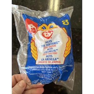 May include: Sealed plastic bag featuring a Ty Nuts the Squirrel toy animal. The bag has a blue background with yellow and red accents, and the number 8. Text includes "Nuts the Squirrel" and "Toy Animal".