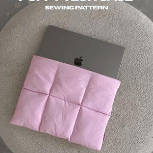 May include: A light pink quilted tech case containing a grey laptop. The text reads: PUFFY TECH CASE SEWING PATTERN, A4+US LETTER | PRINTABLE PDF, 2 SIZES | IPAD + MACBOOK. The case features a grid-like stitched pattern and a soft, padded texture.