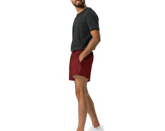 Könnte beinhalten: Eine Person trägt ein dunkelgraues T-Shirt und bordeauxfarbene Shorts. Die Shorts haben Taschen und die Person trägt weiße Turnschuhe. Der Hintergrund ist weiß.