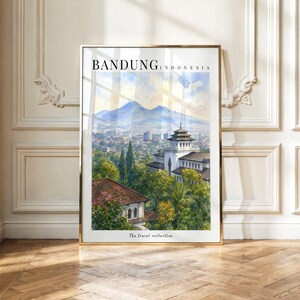 Op de afbeelding: Een ingelijste verticale kunstdruk met een aquarellandschap van Bandung, Indonesië. De scène toont een gebouw met meerdere verdiepingen omringd door groene bomen, met bergen in de verte onder een zachte lucht. De tekst luidt BANDUNG INDONESIA.