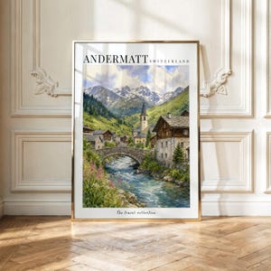 May include: A vertical wall art print featuring a landscape painting of Andermatt, Switzerland. The scene depicts a stone bridge over a river, a village with a church steeple, and snow-capped mountains. Text reads ANDERMATT SWITZERLAND and The travel collection.