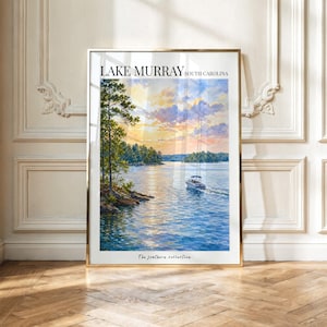 May include: A framed vertical art print featuring a watercolour painting of Lake Murray, South Carolina. The scene depicts a motorboat on blue water at sunset with orange and purple clouds above, framed by trees. Text reads Lake Murray and The Southern collection.