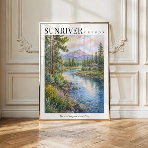May include: A vertical wall art print titled SUNRIVER OREGON featuring a landscape painting of a river flowing through a forest toward a mountain peak under a soft sky. The text The northwestern collective is printed at the bottom of the white border.