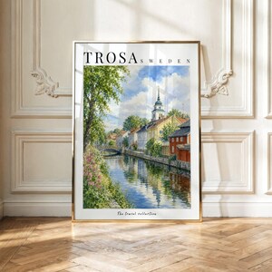 Puede incluir: Una impresión artística vertical enmarcada titulada Trosa Sweden que presenta una acuarela de una escena de canal con un puente de piedra, casas coloridas, un campanario y árboles verdes bajo un cielo azul con nubes. El texto dice Trosa Sweden.