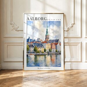 May include: A framed watercolor print of the Aalborg, Denmark waterfront featuring a tall church spire, colorful buildings, and a small sailboat on the water. The text AALBORG DENMARK is printed at the top and The travel collection at the bottom.