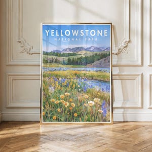 May include: A framed art print featuring a landscape of Yellowstone National Park with the text "YELLOWSTONE NATIONAL PARK" at the top. The scene depicts a field of yellow and blue wildflowers in the foreground, a river, green hills, and mountains.