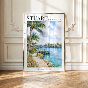 May include: A vertical wall art print featuring a coastal scene of Stuart, Florida. The image displays a blue waterway, a bridge, palm trees, and a stone path with pink flowers. The text STUART FLORIDA is printed at the top, and The coastal collection is at the bottom.