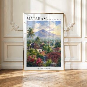 Peut inclure: Une impression d'art encadrée intitulée MATARAM INDONESIA The travel collection, représentant un paysage urbain avec des toits en tuiles rouges, des arbres verts, des fleurs roses et une grande montagne sous un ciel bleu nuageux.