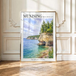 May include: A framed vertical art print featuring a watercolor landscape of Munising, Michigan. The image depicts a rocky cliff formation with green pine trees overlooking blue water. The text reads MUNISING MICHIGAN and The midwestern collection.