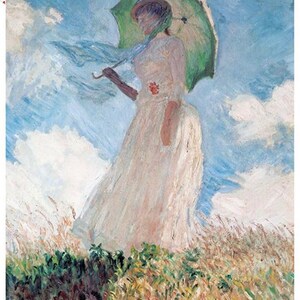May include: A woman in a white dress holds a green umbrella while standing in a field of tall grass. The sky is blue with white clouds.