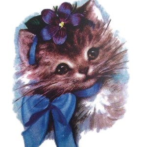 Może przedstawiać: Brązowe i białe kocię z niebieską kokardką i fioletowym kwiatem na głowie.