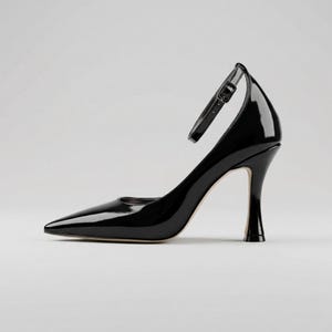 Peut inclure: Une escarpin noir verni avec un bout pointu et une bride de cheville. Le talon aiguille mesure environ 7.6 cm de haut. La chaussure a un design &eacute;l&eacute;gant et moderne, adapt&eacute; aux occasions formelles.
