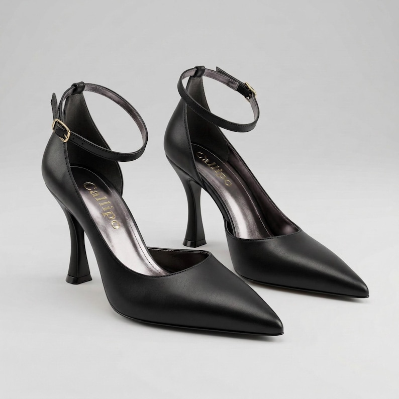 Peut inclure: Une paire d'escarpins noirs en cuir avec des bouts pointus et des brides de cheville. Les talons ont un design fin et incurv&eacute; et une semelle int&eacute;rieure argent&eacute;e m&eacute;tallique. La marque "Callipo" est visible sur la semelle int&eacute;rieure.