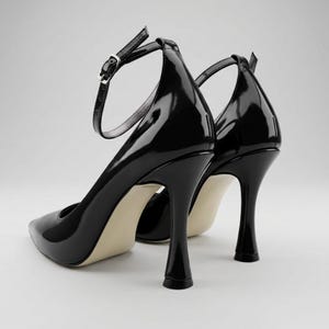 Peut inclure: Paire d'escarpins noirs en cuir verni avec brides de cheville. Les chaussures ont un bout pointu et un talon aiguille. Les talons mesurent environ 10 cm de haut.