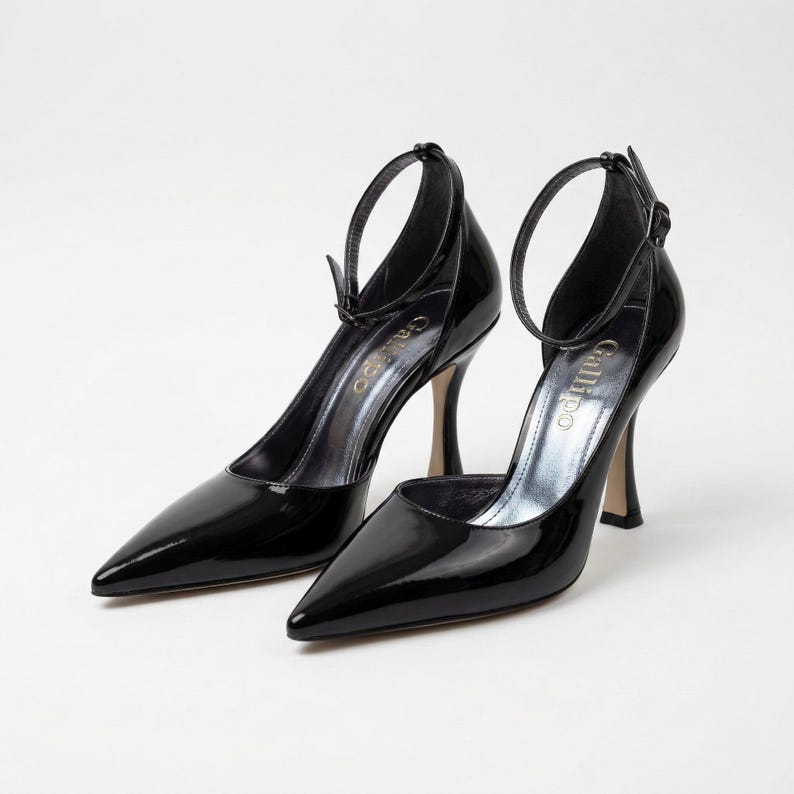 Peut inclure: Paire d'escarpins noirs en cuir verni &agrave; bout pointu et bride de cheville. Les talons aiguilles ont une finition m&eacute;tallique et le nom de la marque "Gallipo" est visible sur la semelle int&eacute;rieure.