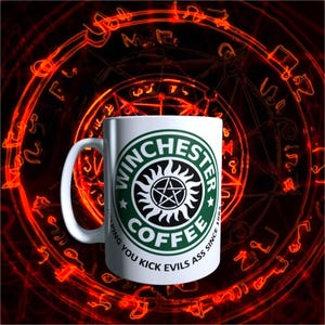 May include: White ceramic coffee mug with the text "Winchester Coffee" in a green and black logo, with the words "Helping you kick evils ass since 1983". The mug is set against a red and black background.