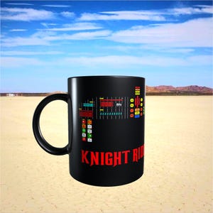 Pode incluir: Caneca de cerâmica preta com um design de painel e o texto vermelho "KNIGHT RIDER". A caneca tem uma alça preta e um gráfico colorido de um painel de carro. A caneca está situada em uma paisagem desértica com céu azul.
