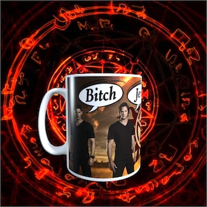 May include: White ceramic mug featuring two men in black shirts with the words "Bitch" and "Jerks" in speech bubbles. The mug has a black and red background with a circular design.