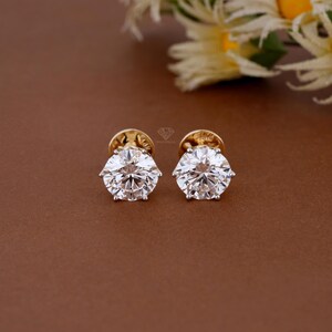 Peut inclure: Une paire de boucles d'oreilles à clous avec des pierres rondes transparentes taille brillant montées sur de l'or jaune. Chaque boucle possède un sertissage à six griffes qui maintient la pierre facettée, reflétant la lumière avec éclat.