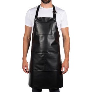 May include: A black apron with a large front pocket and two lower pockets. The apron has adjustable neck and waist straps. The apron is made of a smooth, leather-like material.