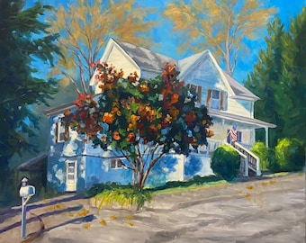 May include: A white house with a red, orange, and green tree in front of it. The house has a porch with a railing and a flag hanging from it. The house is surrounded by green grass and trees.