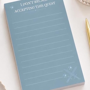 May include: A blue notepad with the text "I DON'T RECALL ACCEPTING THIS QUEST" in white. The notepad has horizontal lines for writing and a crossed swords graphic. A gold pen is visible in the background.