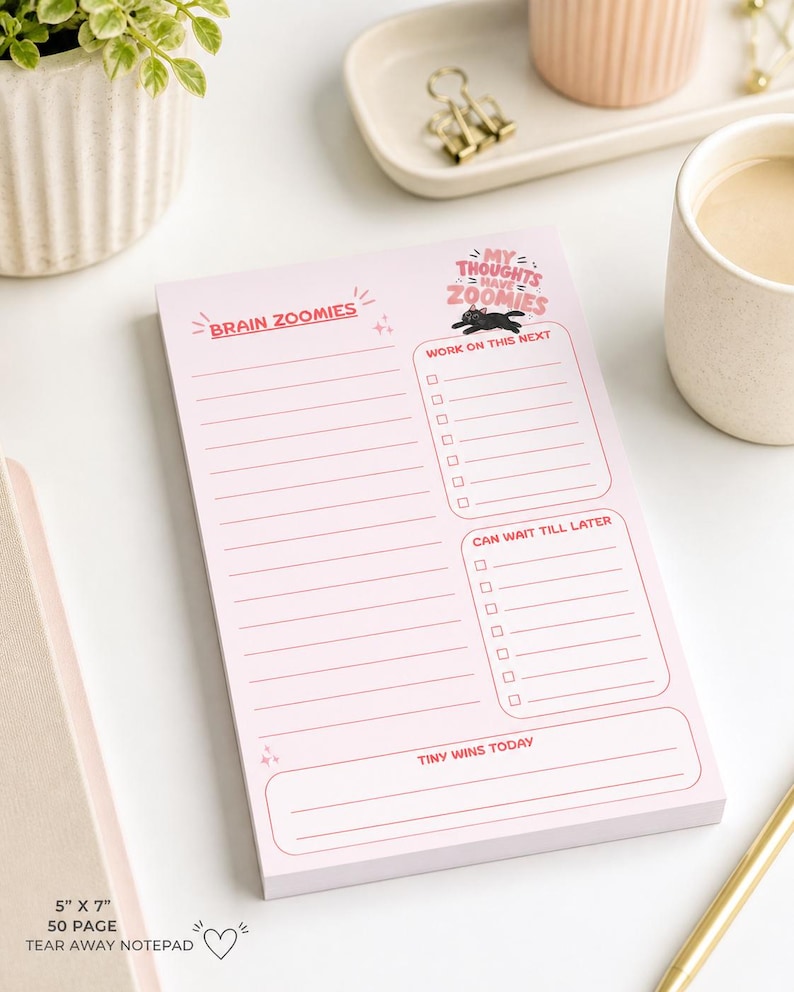 May include: Pink tear-away notepad with the text "Brain Zoomies" and "My Thoughts Have Zoomies." The notepad includes sections for to-do lists and notes, measuring 5" x 7". A black cat graphic is also included.