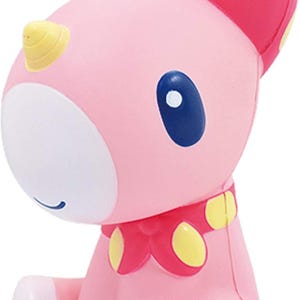May include: A pink unicorn figurine with a yellow horn and blue eyes. The unicorn has pink ears with yellow polka dots, a pink bow, and a pink tail. The figurine is sitting down.