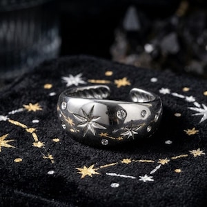 Può includere: Una tazza di ceramica bianca con manico nero e la scritta "But First, Coffee" in nero, in grassetto. La tazza è appoggiata su una superficie di legno. La tazza è alta circa 10 cm.