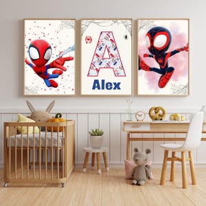 Può includere: Tre opere d'arte da parete a tema supereroi incorniciate. Una presenta Spider-Man, un'altra mostra la lettera "A" con un motivo, e la terza presenta un altro personaggio di Spider-Man. Il nome "Alex" è sotto la lettera "A". L'arte è esposta nella cameretta di un bambino.