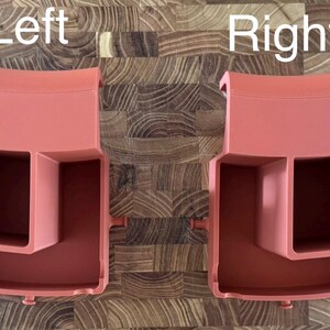 May include: Two coral-colored plastic organizers, labeled "Left" and "Right", are displayed. Each organizer has a rectangular compartment, a smaller square compartment, and three circular holes. The organizers are designed to hold various items.