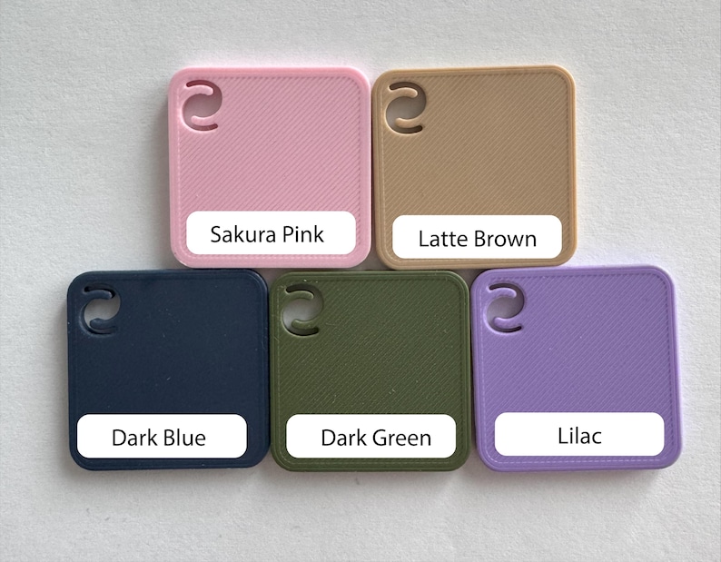 May include: Five square color swatches in Sakura Pink, Latte Brown, Dark Blue, Dark Green, and Lilac. Each swatch has a rounded corner and a curved cutout. Each swatch has a white label with the color name.