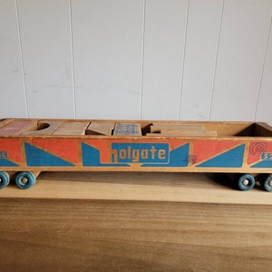 May include: Vintage wooden toy truck with a red, blue, and white paint scheme. The truck has a Holgate logo and the number 529 on the side. The truck is loaded with wooden blocks.
