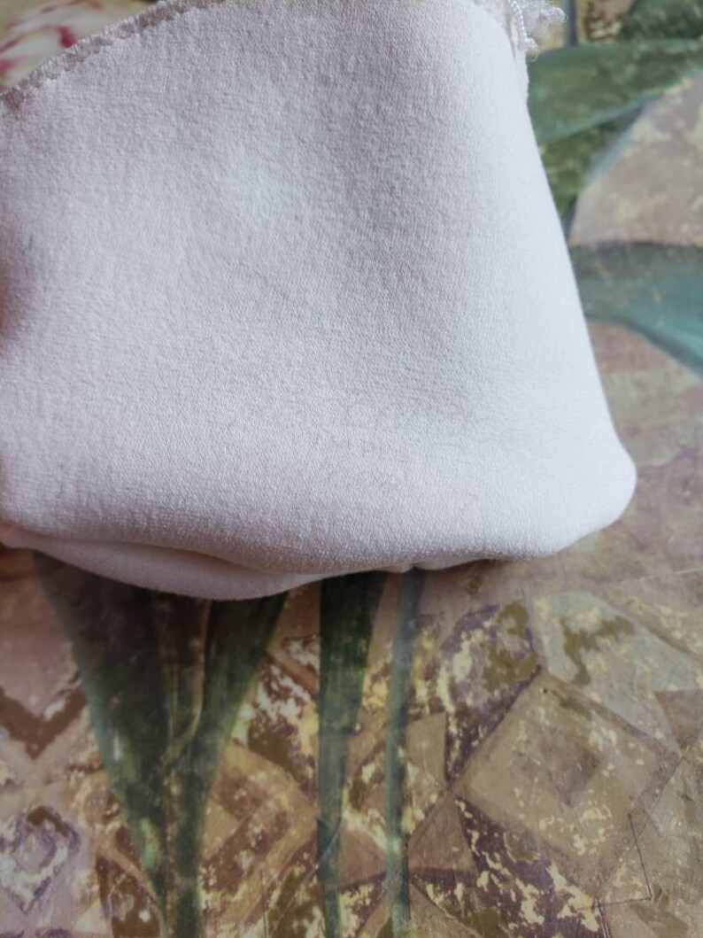 May include: A close-up of a white fabric with a soft, textured surface. The fabric is folded and appears to be a piece of clothing or a home decor item.