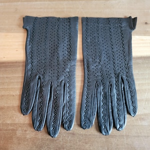 May include: A pair of black leather gloves with a perforated design and scalloped edges.