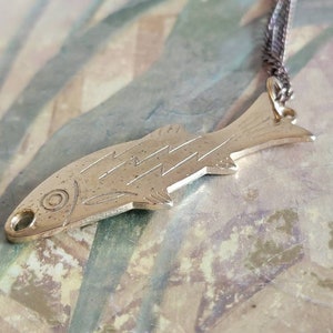 May include: A silver fish pendant necklace with a detailed design. The pendant is attached to a silver chain.