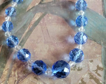 May include: A necklace made of alternating clear and blue faceted glass beads.