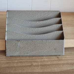 May include: A gray, rectangular, textured desk organizer with five compartments. The organizer is made of a rough, textured material.