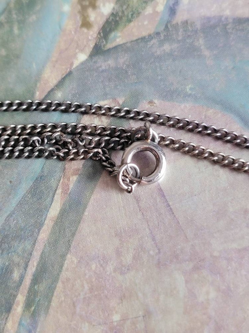 May include: Close-up of a silver chain necklace with a lobster clasp closure.