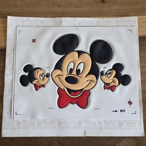 May include: A Dimension Weld sticker featuring Mickey Mouse with a red bow tie and two smaller Mickey Mouse figures. The main Mickey Mouse has a tan face, black ears, and a red bow tie. The sticker is on a white background.